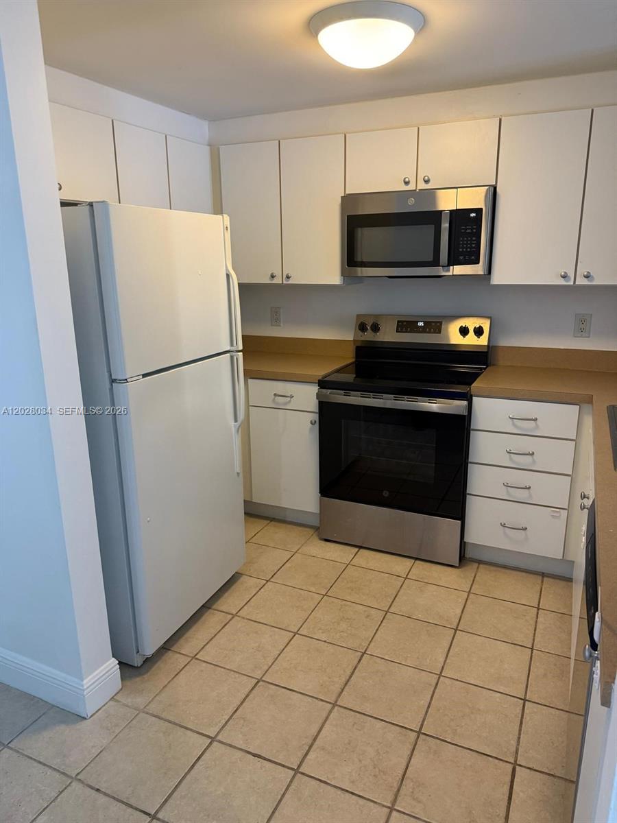 A kitchen features white cabinets, stainless steel appliances, tan countertops, and light-colored tile flooring — 1250 S Miami Ave # 1412, Miami FL 33130, MIAMI, FL