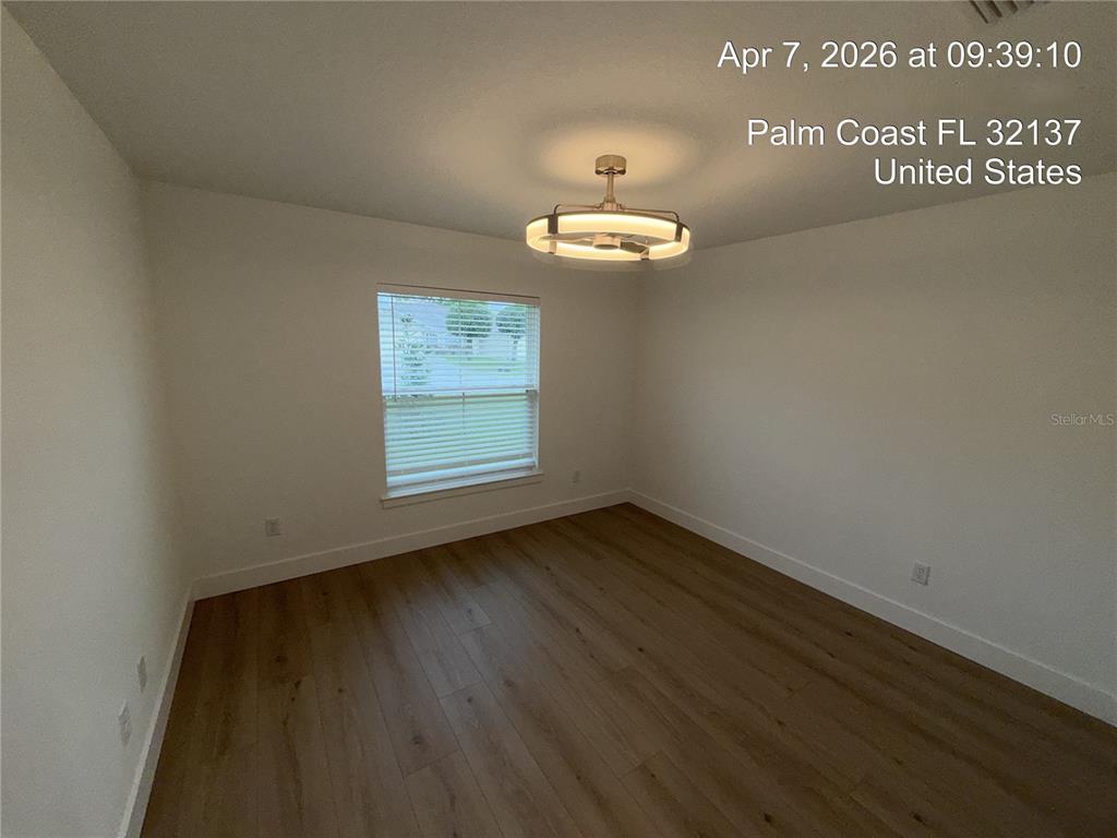 An empty bedroom features light wood-look flooring, white walls, and a modern circular light fixture — 85 LARAMIE DRIVE, PALM COAST, FL