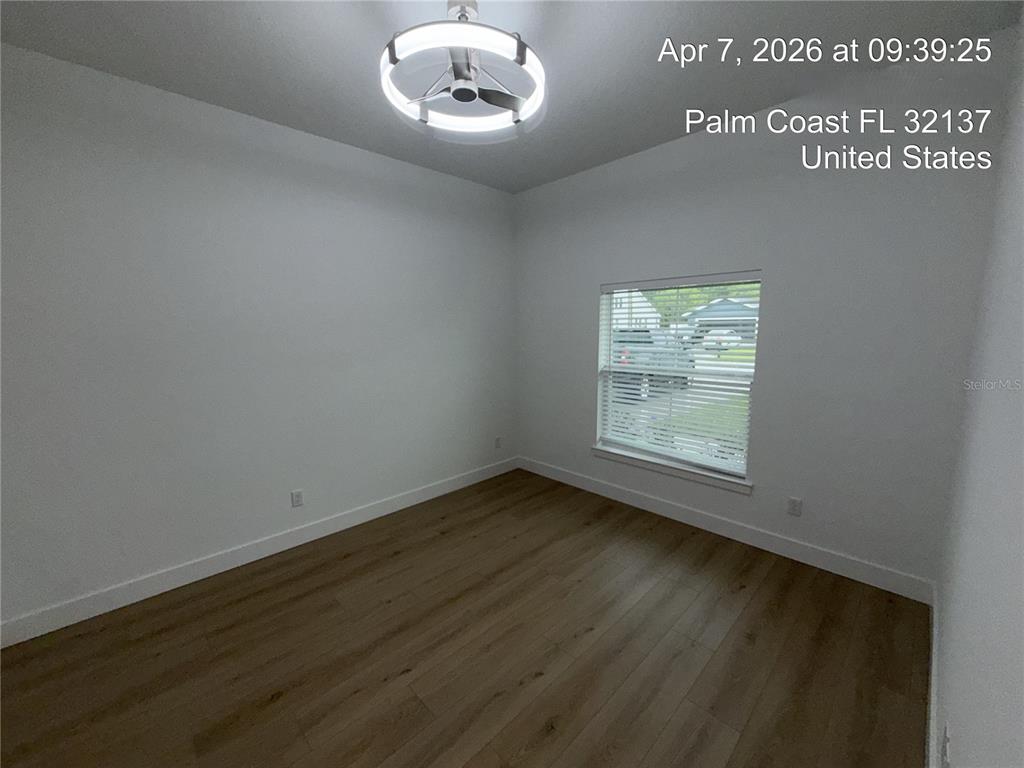An empty bedroom features white walls, wood-look flooring, and a modern circular ceiling light fixture — 85 LARAMIE DRIVE, PALM COAST, FL