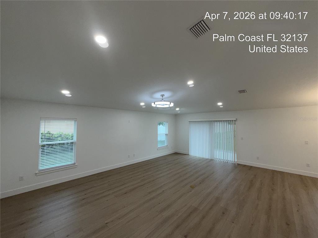 An empty room features light wood-look flooring, white walls, recessed lighting, and vertical blinds — 85 LARAMIE DRIVE, PALM COAST, FL