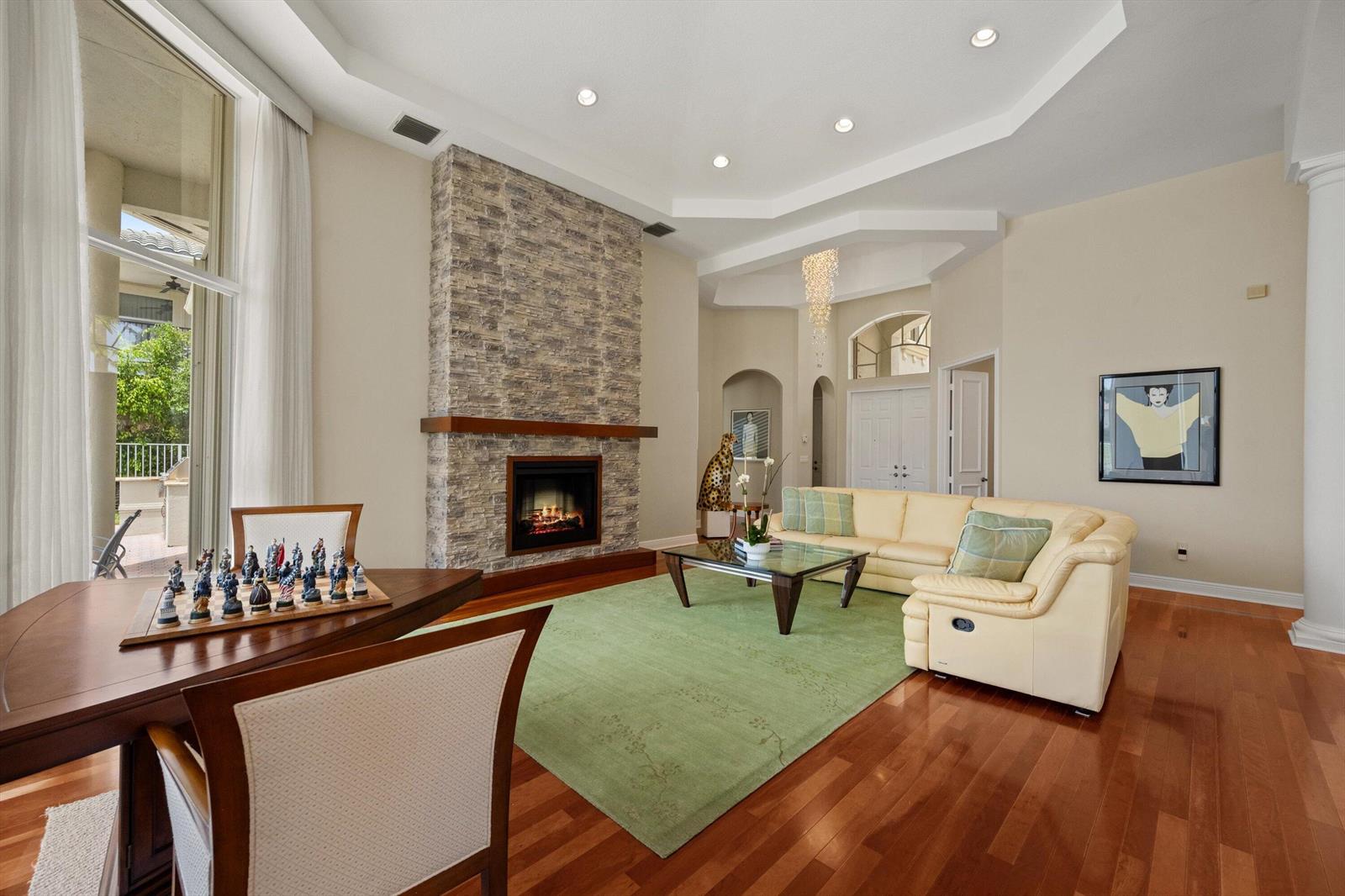 A living room features a stone fireplace, a cream sectional, and a chess set table — 2792 Pillsbury Way, Wellington FL 33414, WELLINGTON, FL