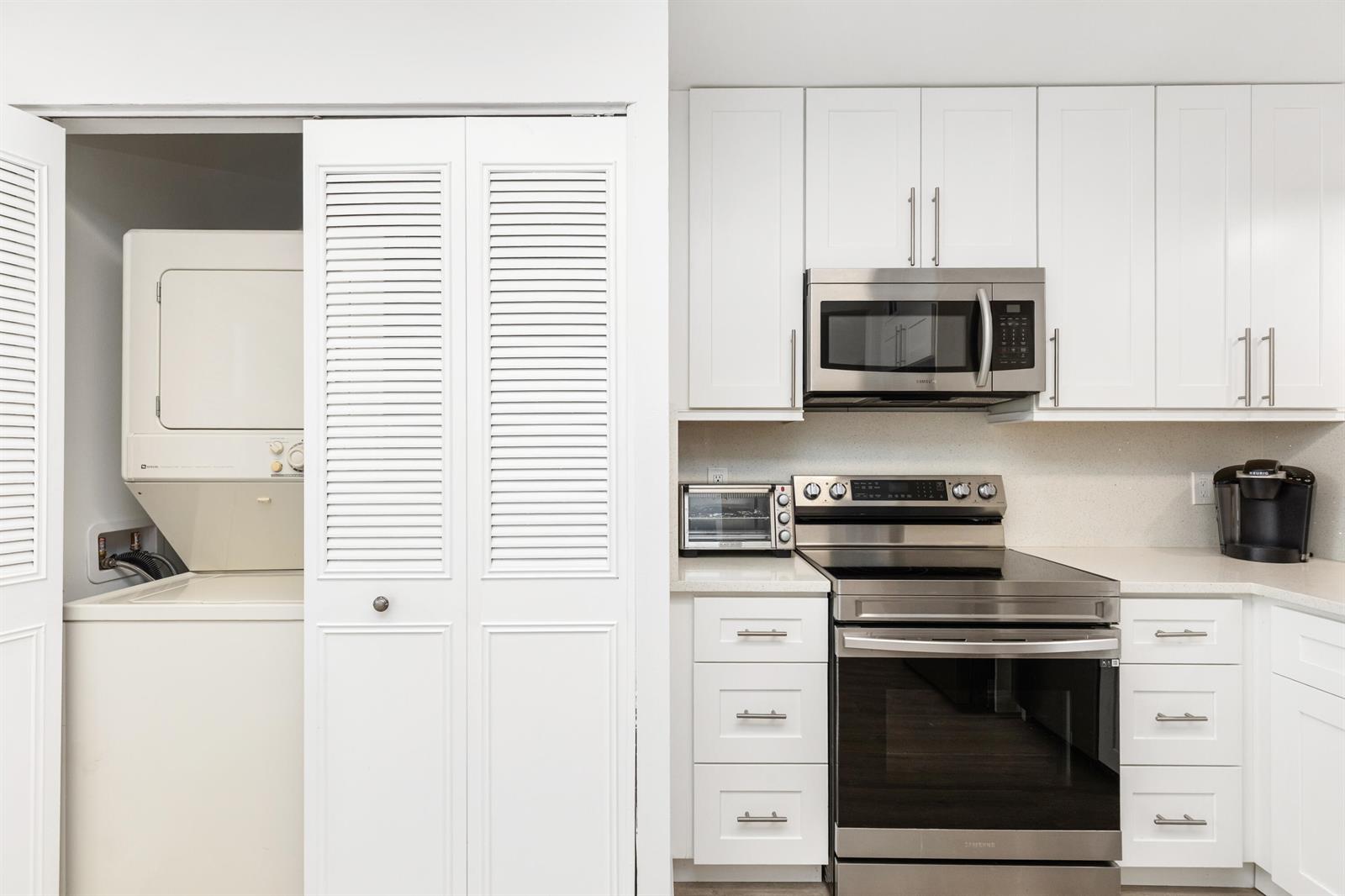 A kitchen with white cabinets and stainless steel appliances next to a laundry closet — 6650 S Oriole Boulevard # 4080, Delray Beach FL 33446, DELRAY BEACH, FL