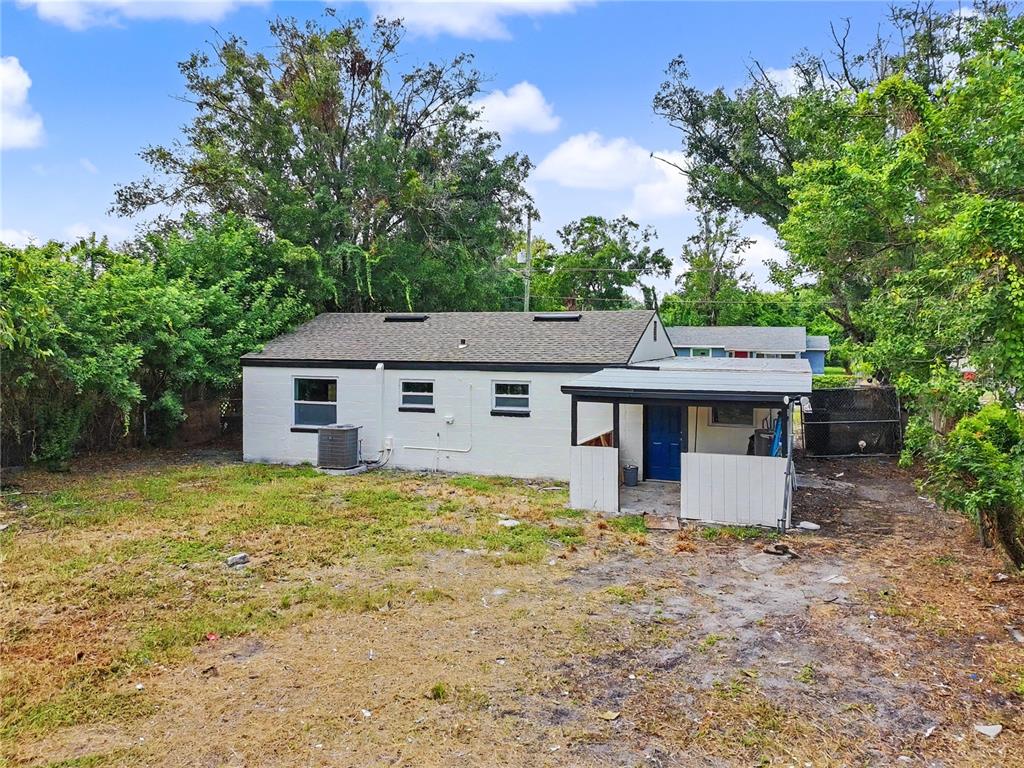 The exterior of a white, single-story house with a small covered porch and backyard — 2848 W HARWOOD STREET, ORLANDO, FL