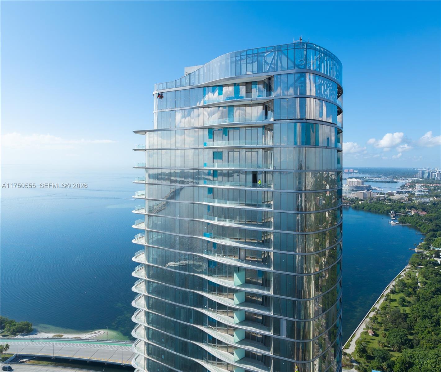 An aerial view shows a modern glass high-rise building situated along a waterfront — 175 SE 25 RD # 3902, Miami FL 33129, MIAMI, FL