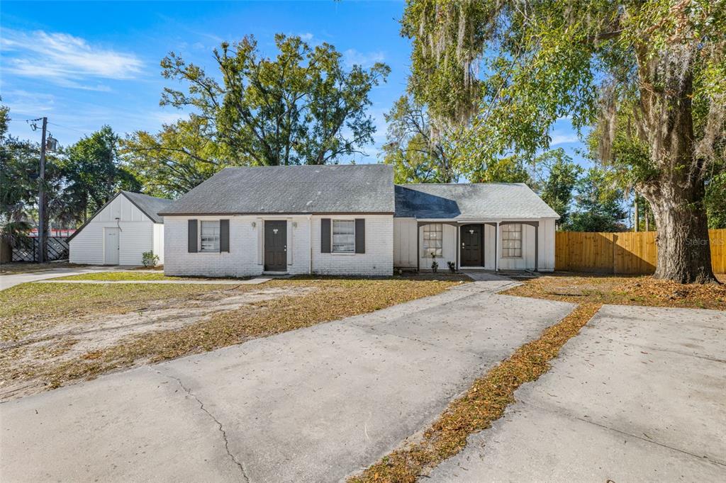 A white, single-story house with a concrete driveway and a detached garage under trees — 1403 COLLEGE PARK LANE, TAMPA, FL