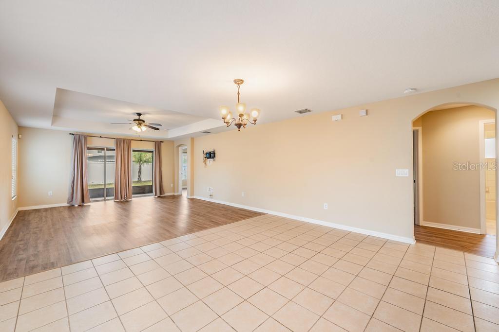 A spacious living area features a combination of tile and wood-look flooring with a chandelier — 7013 FOREST MERE DRIVE, RIVERVIEW, FL