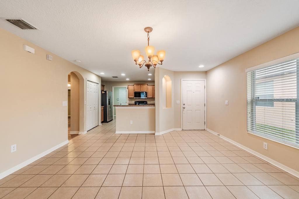 An open-concept dining area with tile flooring, a chandelier, and a view into the kitchen — 7013 FOREST MERE DRIVE, RIVERVIEW, FL