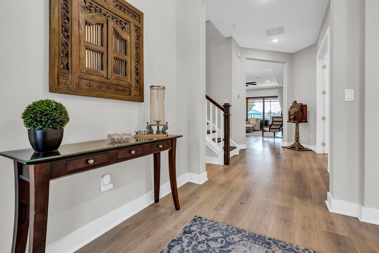 A foyer features a wooden console table, a decorative wall hanging, and wood-look flooring — 15829 Key Biscayne Lane, Westlake FL 33470, WESTLAKE, FL