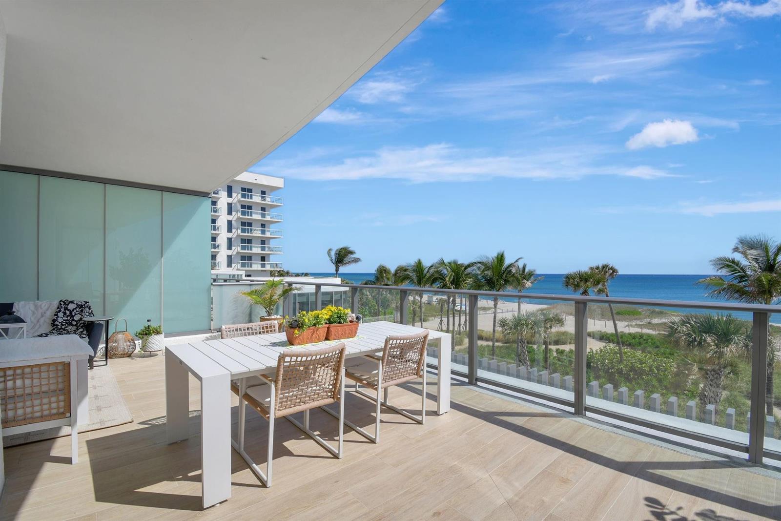 A modern balcony features a dining table, outdoor seating, and a view of the ocean — 1116 N Ocean Boulevard # 303, Pompano Beach FL 33062, POMPANO BEACH, FL
