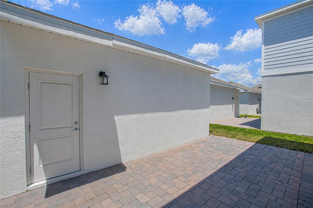 A paved patio area sits between two white stucco buildings under a blue sky — 1844 BRIGHT SKY DRIVE, KISSIMMEE, FL