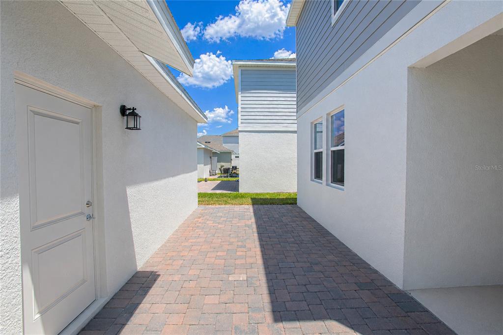 A paved walkway sits between two white stucco houses under a blue sky — 1844 BRIGHT SKY DRIVE, KISSIMMEE, FL