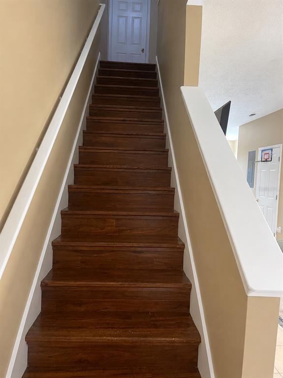 A straight wooden staircase with white railings leads to a landing with a closed door — 11517 DECLARATION DRIVE, TAMPA, FL