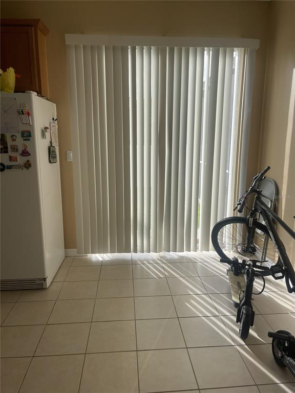 A kitchen area features a white refrigerator, vertical blinds over a sliding door, and tile flooring — 11517 DECLARATION DRIVE, TAMPA, FL