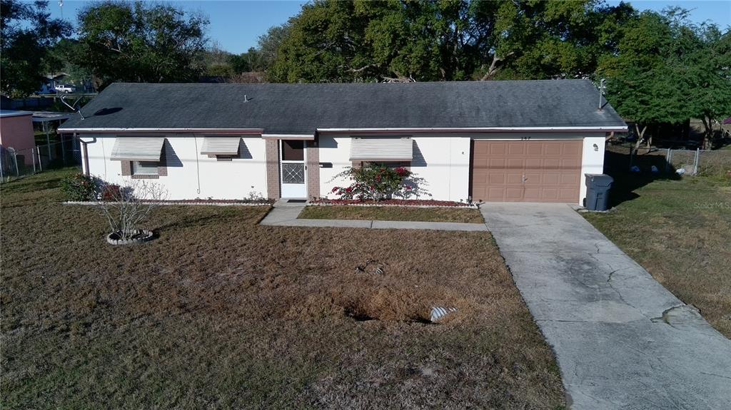 A single-story house with a white exterior, gray shingled roof, and an attached garage — 147 EVERGREEN DRIVE, LAKE WALES, FL