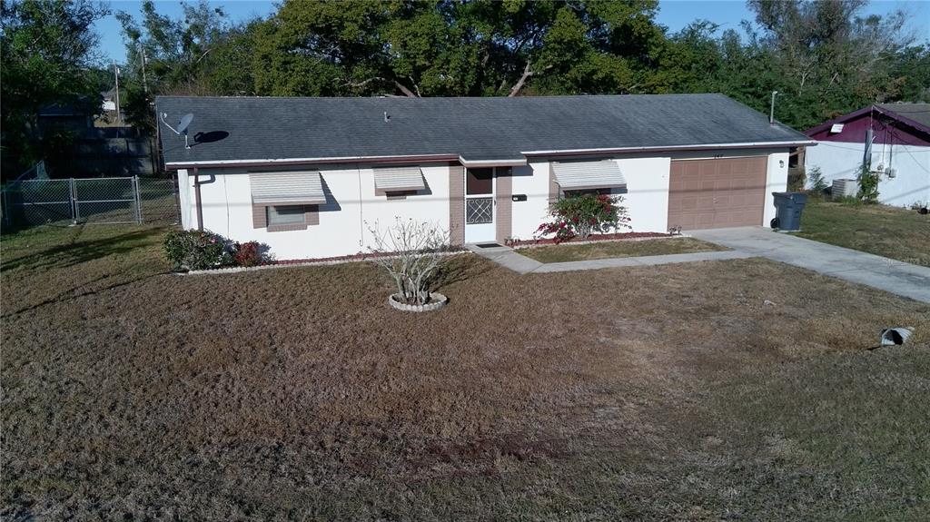 An aerial view shows a single-story house with a white exterior, gray roof, and garage — 147 EVERGREEN DRIVE, LAKE WALES, FL