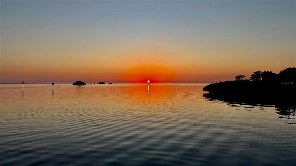 A vibrant sunset over a calm body of water with small islands and navigation markers — 1430 MANATEE CIRCLE, TARPON SPRINGS, FL