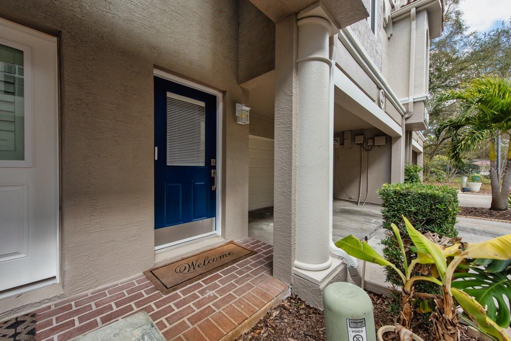 A blue front door with a welcome mat sits under a covered porch with columns — 1430 MANATEE CIRCLE, TARPON SPRINGS, FL