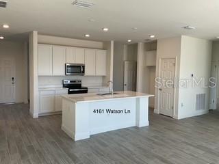 A kitchen features white cabinets, stainless steel appliances, and a central island with a sink — 4161 WATSON AVENUE, NORTH PORT, FL