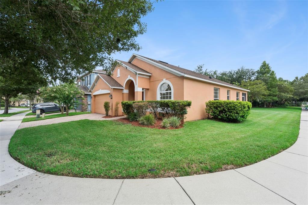 A single-story peach-colored house with a paved driveway and a manicured lawn on a corner — 12751 MOSS PARK RIDGE DRIVE, ORLANDO, FL