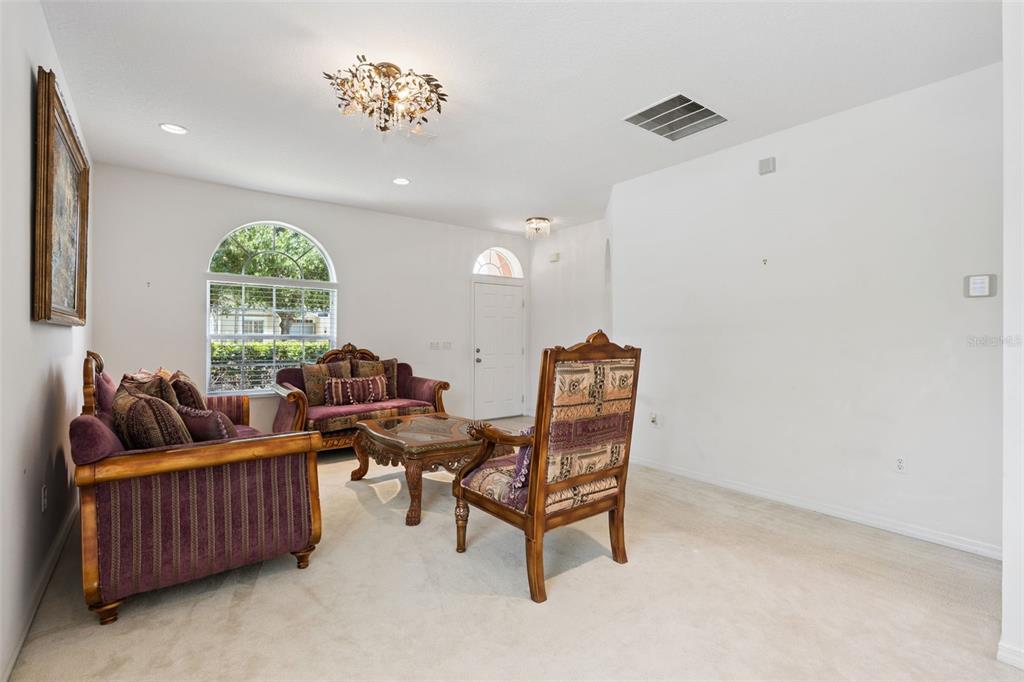 A living room features a purple sofa set, a coffee table, and a large arched window — 12751 MOSS PARK RIDGE DRIVE, ORLANDO, FL