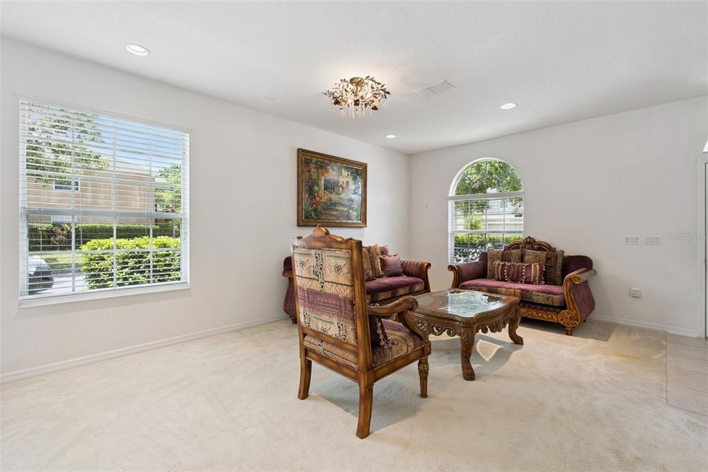 A living room features beige carpeting, two sofas, an armchair, and a coffee table — 12751 MOSS PARK RIDGE DRIVE, ORLANDO, FL