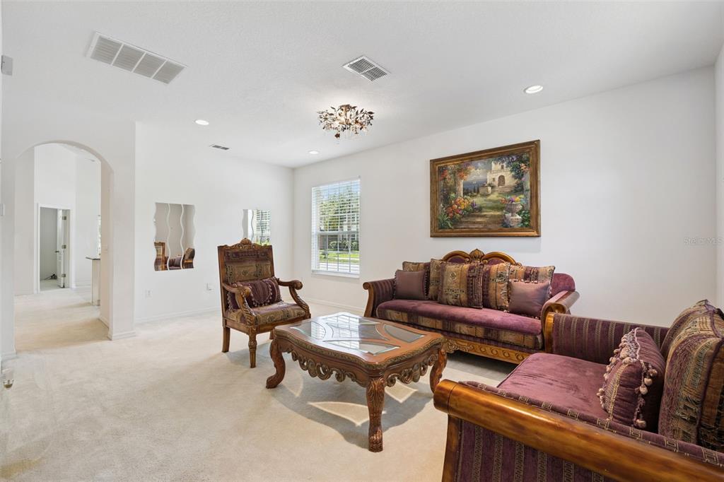 A living room features purple upholstered furniture, a wooden coffee table, and a large painting — 12751 MOSS PARK RIDGE DRIVE, ORLANDO, FL