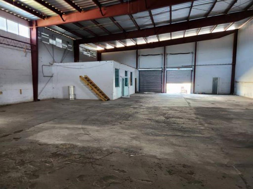 An interior view of a large industrial warehouse with concrete floors and two roll-up doors — 20 REPARADA INDUSTRIAL PARK, 4TH ST. LOT 20, PONCE, PR