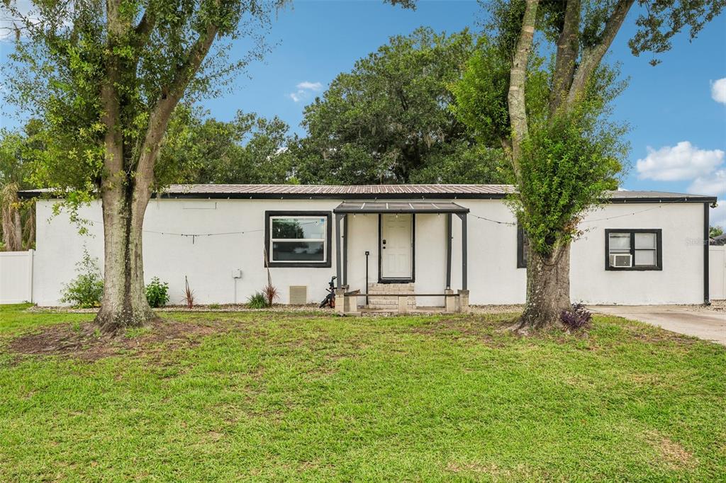 A single-story white house with a metal roof and a small covered front porch — 8620 INDIAN RIDGE TRAIL, LAKELAND, FL