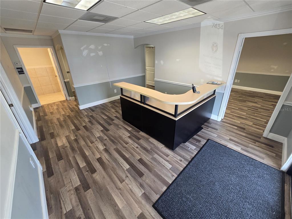 A reception area features a wooden desk, wood-look flooring, and a drop ceiling — 7434 S FEDERAL HWY 1 HIGHWAY, PORT ST LUCIE, FL