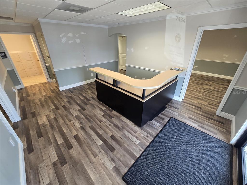 A reception area features a wood-look laminate floor, a black and tan desk, and grey walls — 7434 S FEDERAL HWY 1 HIGHWAY, PORT ST LUCIE, FL