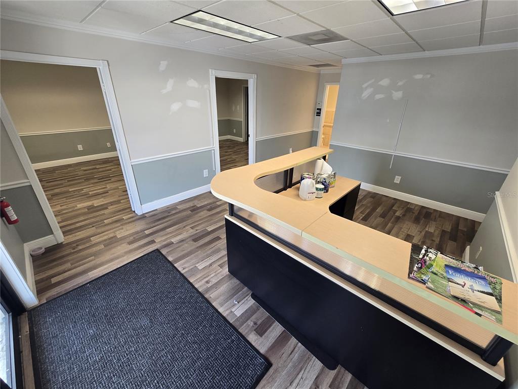 An office reception area features a curved desk, wood-look flooring, and two doorways leading inside — 7434 S FEDERAL HWY 1 HIGHWAY, PORT ST LUCIE, FL