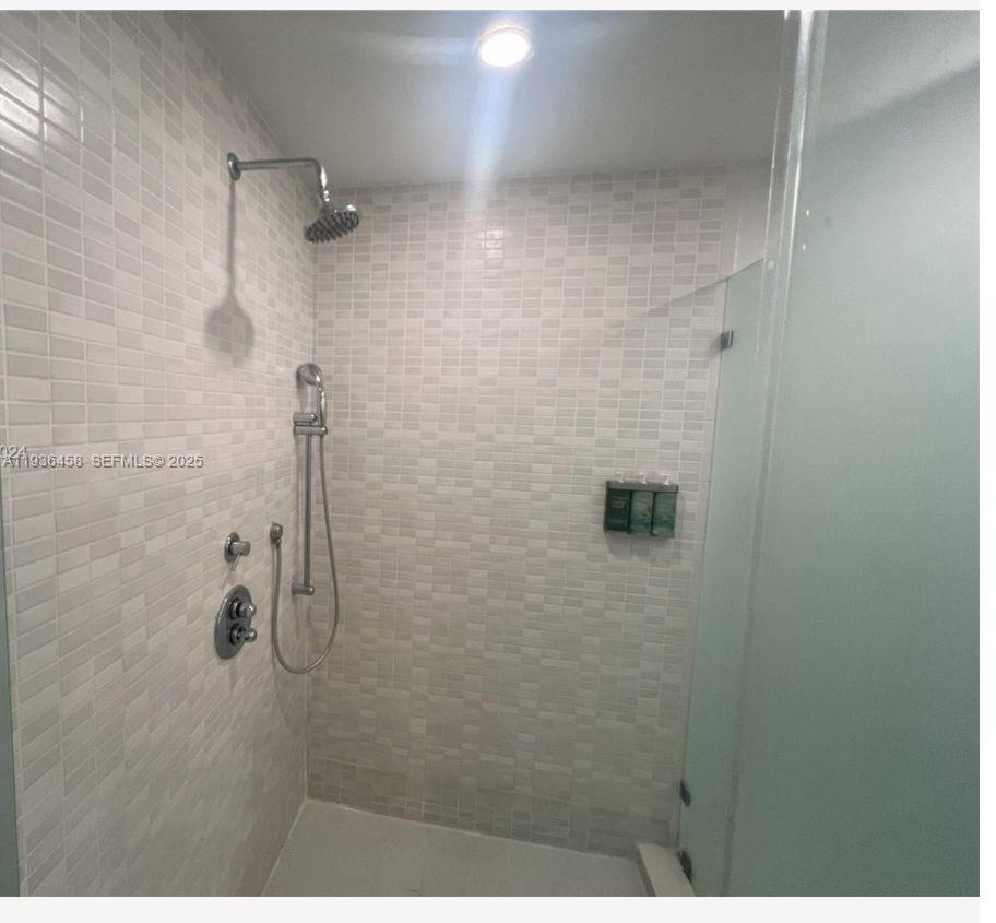 A walk-in shower with light-colored tiled walls, a glass door, and dual showerheads — 5300 NW 87th Ave # 601, Doral FL 33178, DORAL, FL