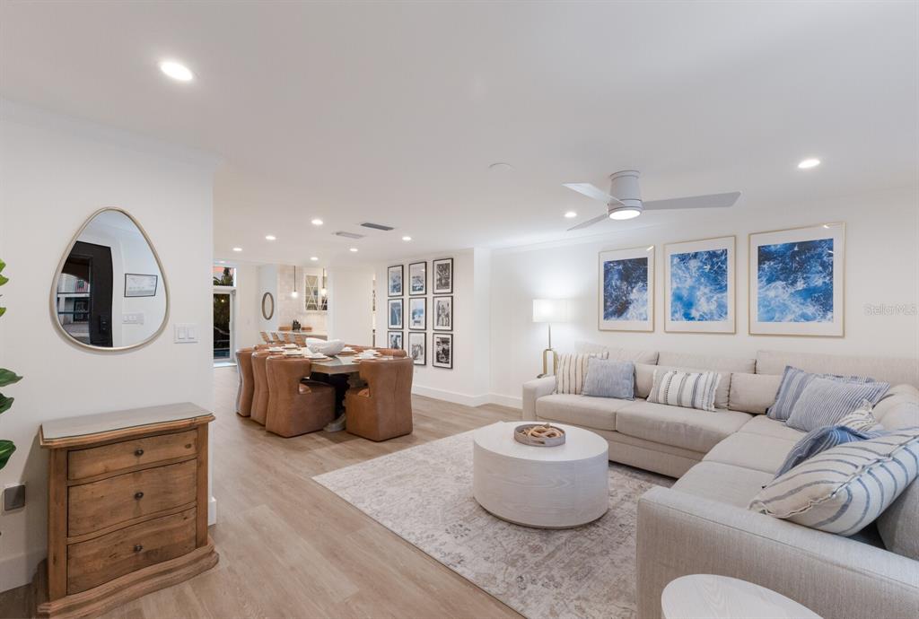 A bright, open-concept living and dining area features light wood floors and neutral furniture — 212 OAK AVENUE, ANNA MARIA, FL