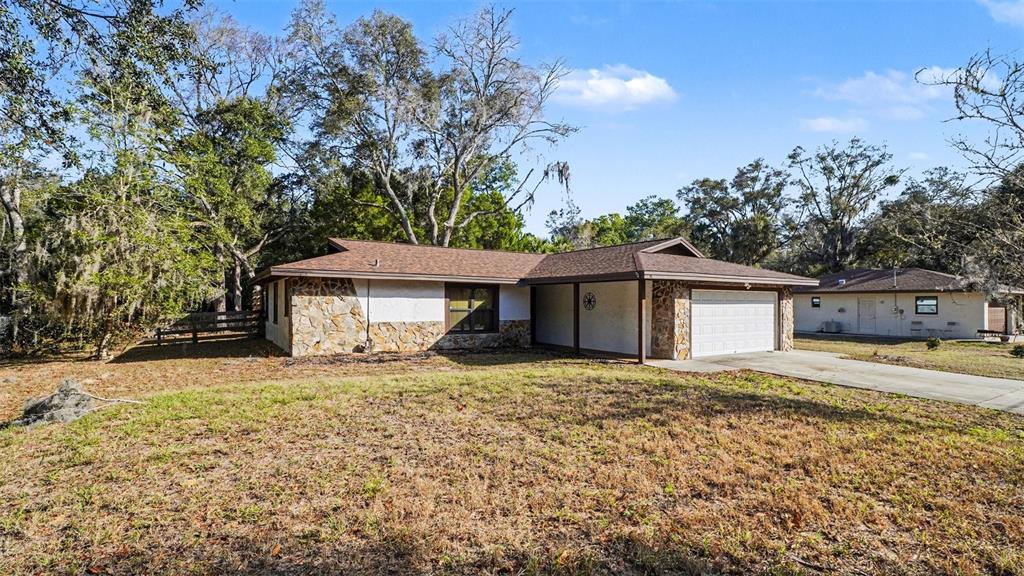 A single-story house with a stone facade, brown roof, and attached garage sits on grass — 11699 W INDIAN CIRCLE, CRYSTAL RIVER, FL