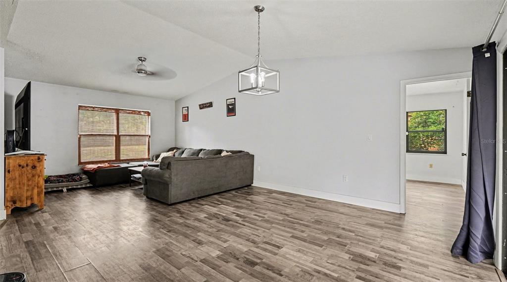 A living room features gray wood-look flooring, a sectional sofa, and a modern pendant light — 11699 W INDIAN CIRCLE, CRYSTAL RIVER, FL