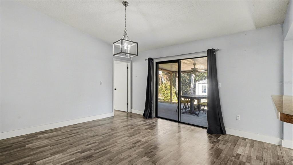 A dining area features wood-look flooring, a modern light fixture, and sliding glass patio doors — 11699 W INDIAN CIRCLE, CRYSTAL RIVER, FL