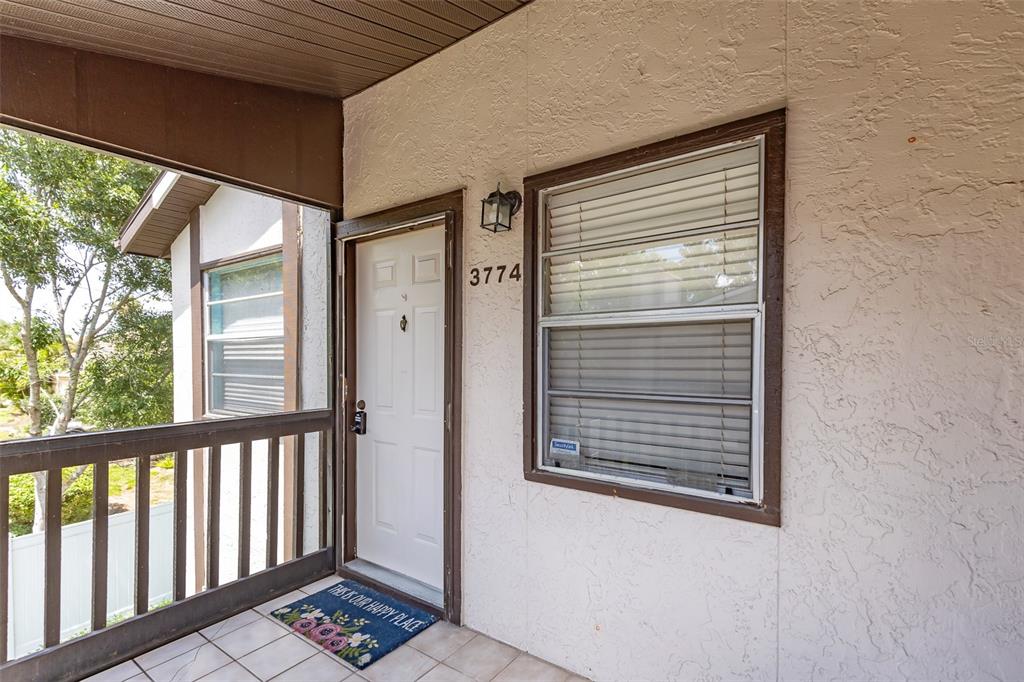 A white front door with a house number sits on a tiled porch with railings — 3774 59TH AVENUE W UNIT 3774, BRADENTON, FL