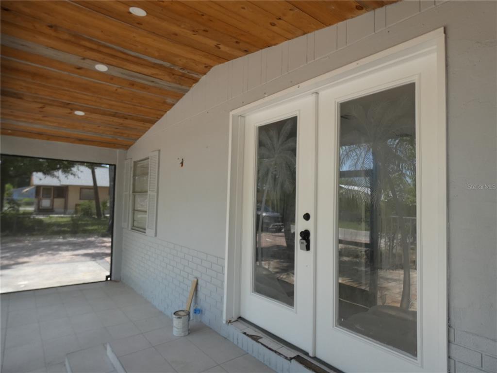 A covered porch features a wood-paneled ceiling, light gray brick walls, and white double doors — 3817 PEARL STREET, FORT MYERS, FL