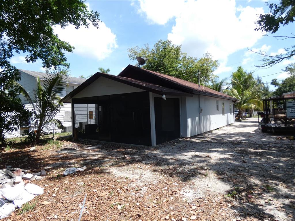 A side view of a single-story house with a screened-in porch and gravel driveway — 3817 PEARL STREET, FORT MYERS, FL