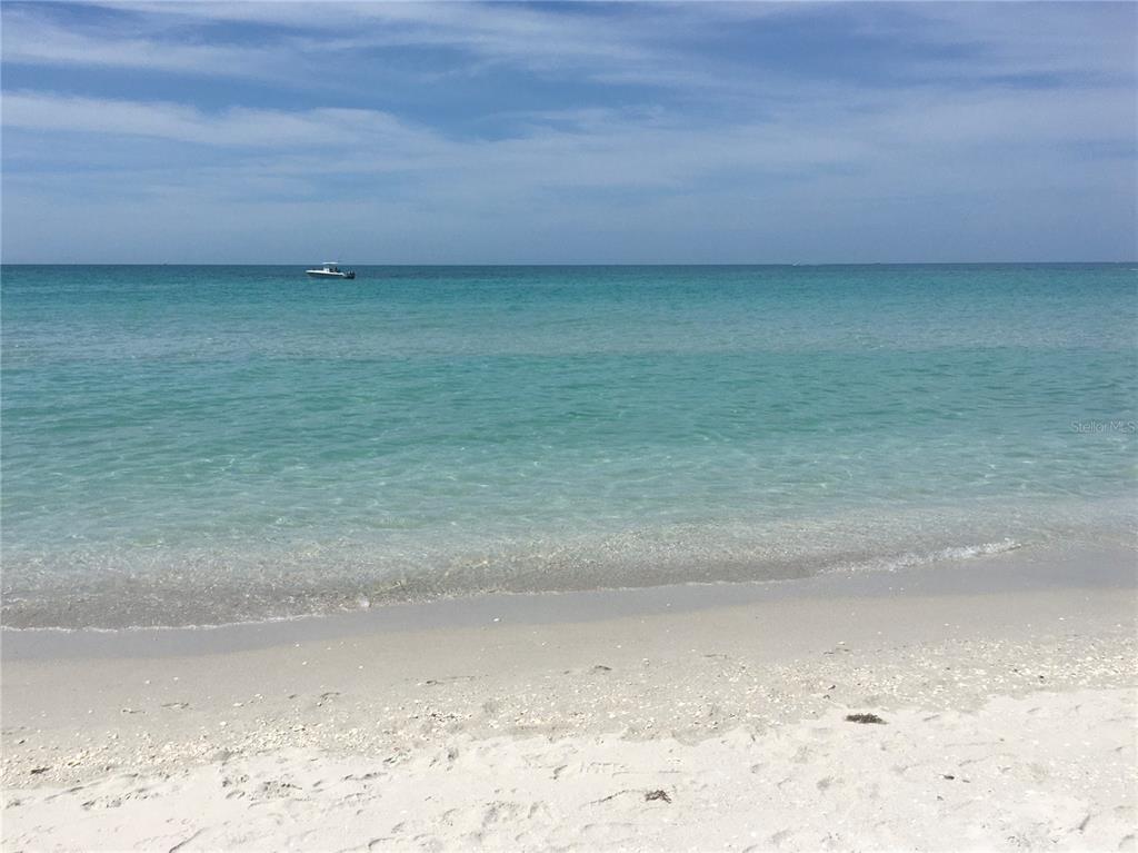 A view of a sandy beach with turquoise water and a boat on the horizon — 1616/1999 COASTAL/BROADPOINT DRIVE, PUNTA GORDA, FL
