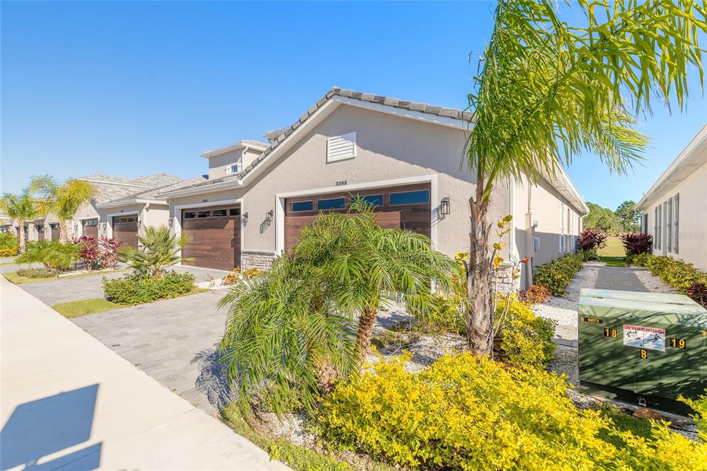 A beige single-story house with a two-car garage and a palm tree in the front — 3088 ISLES WAY, NEW SMYRNA BEACH, FL