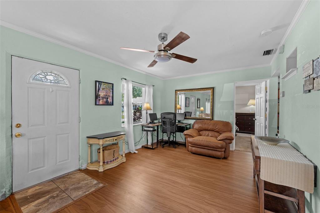 A living room features light green walls, wood-look flooring, a ceiling fan, and a desk — 6737 LAUREL STREET N, ST PETERSBURG, FL