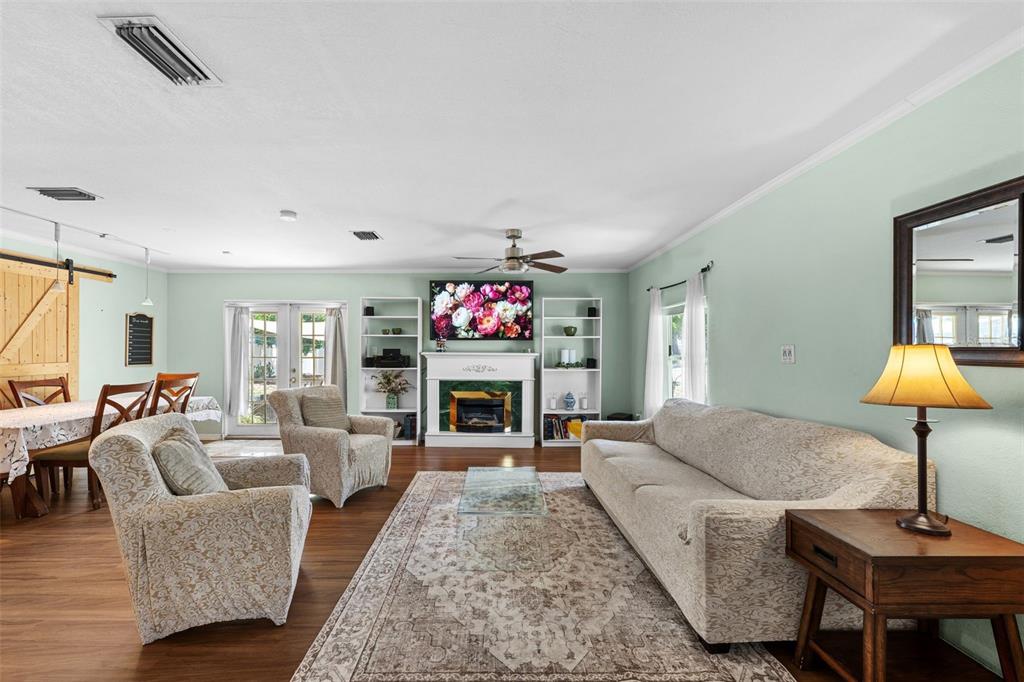A living room features a fireplace, built-in shelving, a sofa, two armchairs, and wood flooring — 6737 LAUREL STREET N, ST PETERSBURG, FL