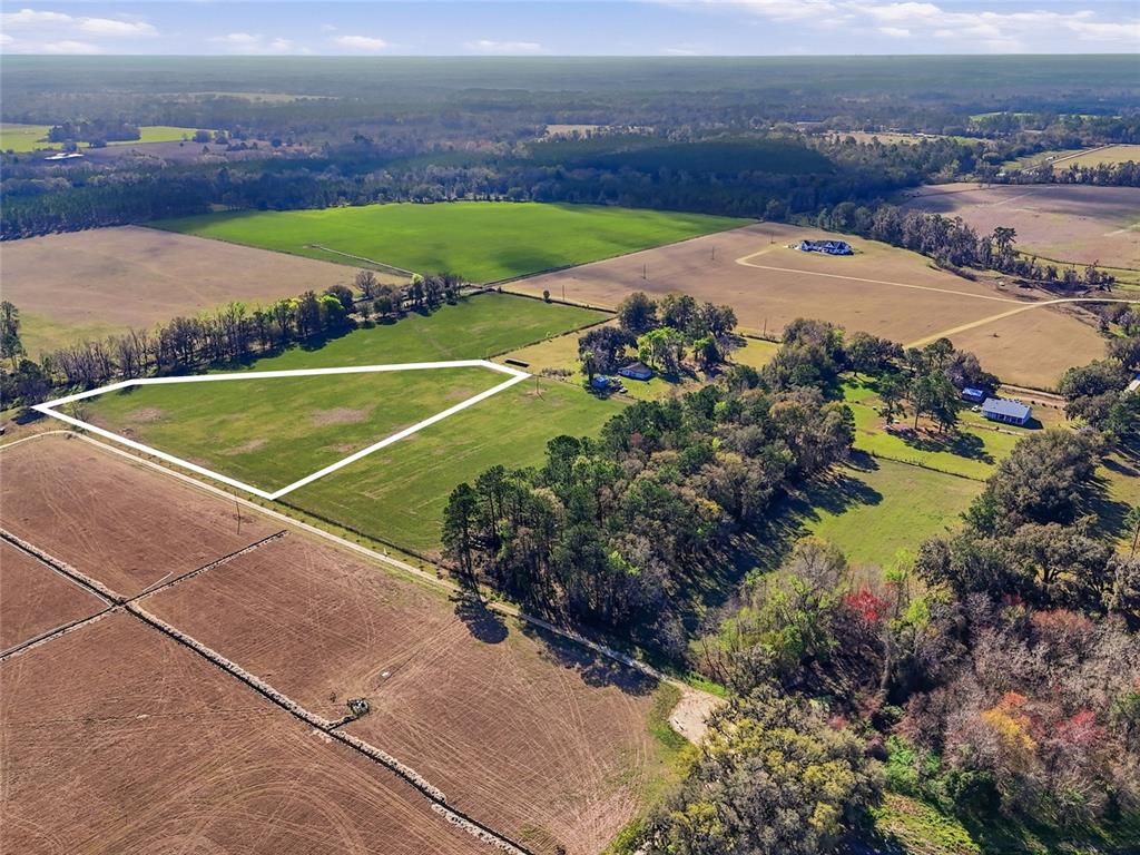 An aerial view shows a triangular parcel of land outlined in white within a rural landscape — NW COUNTY RD 239, ALACHUA, FL