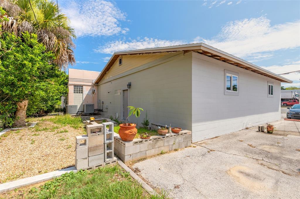 A side view of a light-colored building with a concrete block planter and driveway — 600 N DIXIE FREEWAY, NEW SMYRNA BEACH, FL