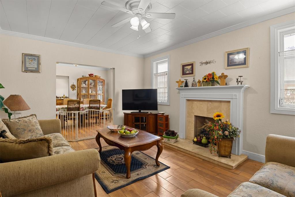 A living room features a fireplace, a ceiling fan, wood flooring, and an adjacent dining area — 207 S PERRY AVENUE, FORT MEADE, FL