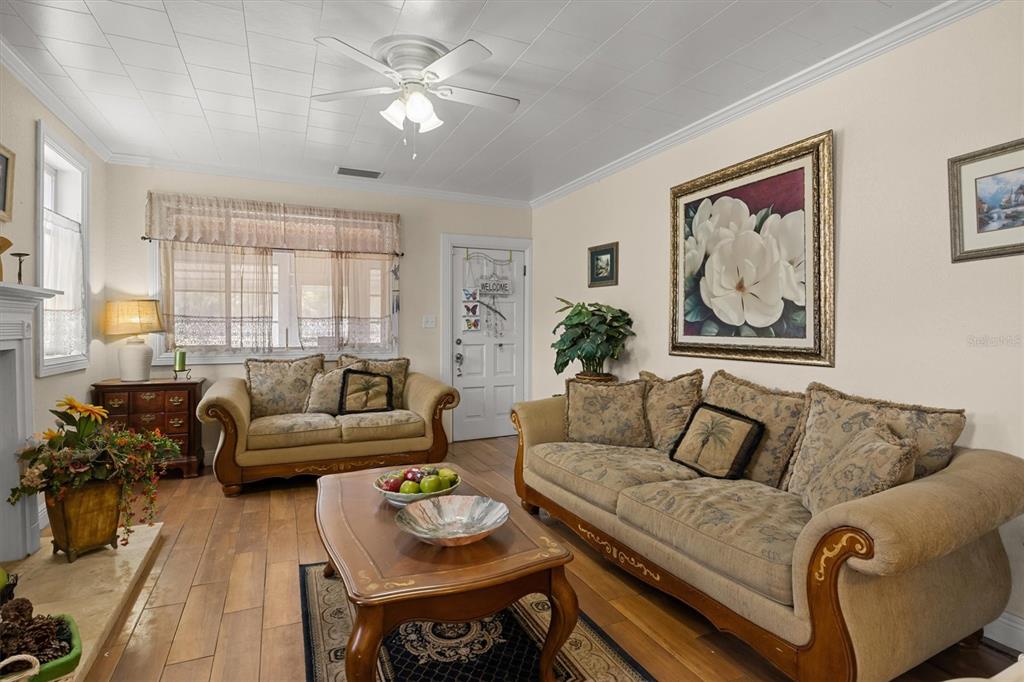 A living room features wood-look flooring, two beige sofas, a coffee table, and a ceiling fan — 207 S PERRY AVENUE, FORT MEADE, FL