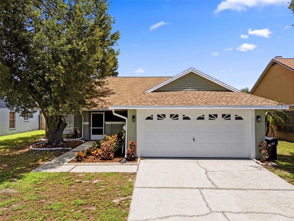 A single-story house with a white garage door, a front walkway, and a large tree — 8723 OSAGE DRIVE, TAMPA, FL