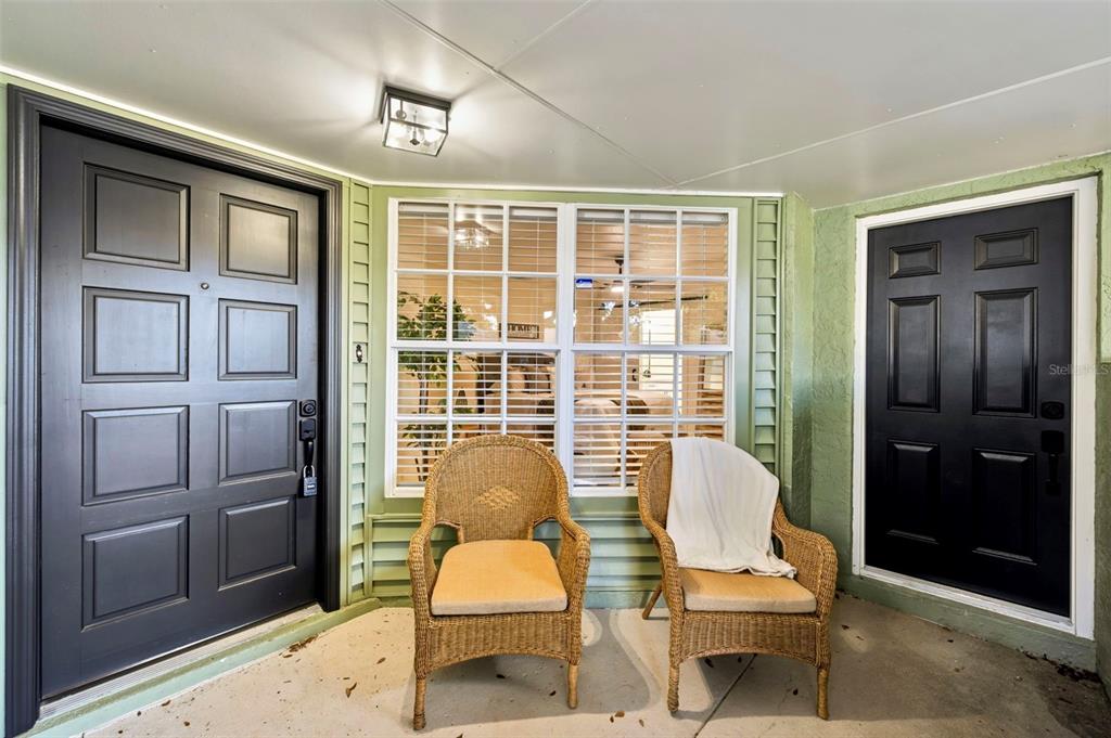 A covered porch features two wicker chairs, a large window, and two black entry doors — 8723 OSAGE DRIVE, TAMPA, FL