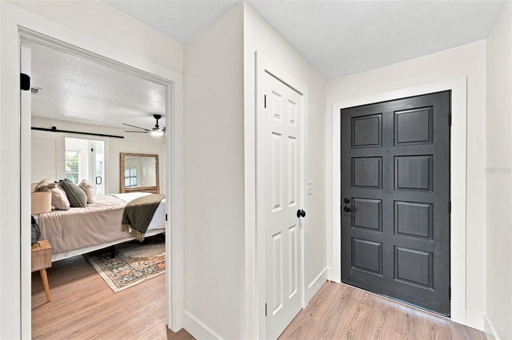 An entryway features wood-look flooring, a dark gray front door, and a white closet door — 8723 OSAGE DRIVE, TAMPA, FL